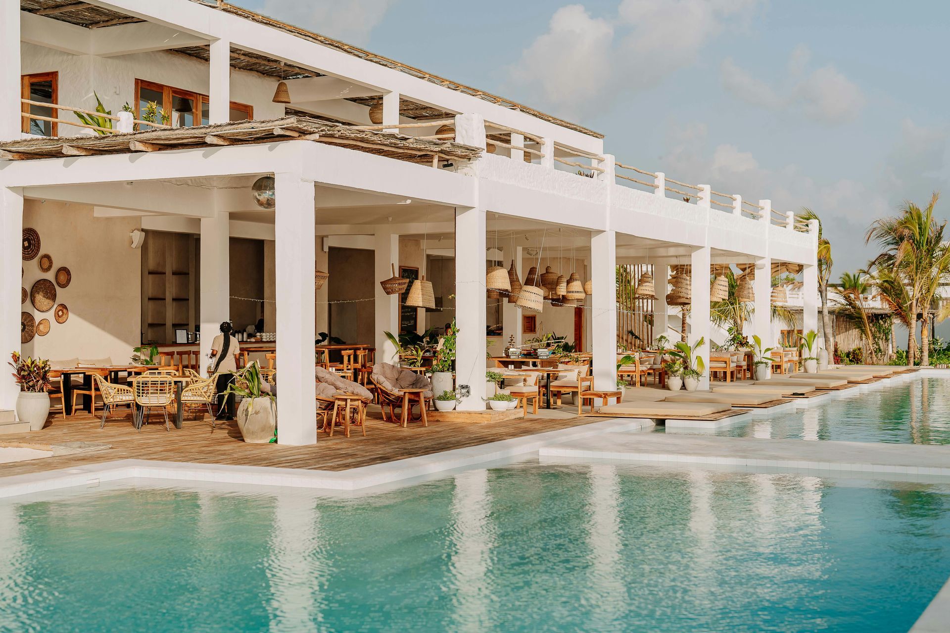 Luxury beachfront resort with white terraces, palm trees, and a turquoise infinity pool