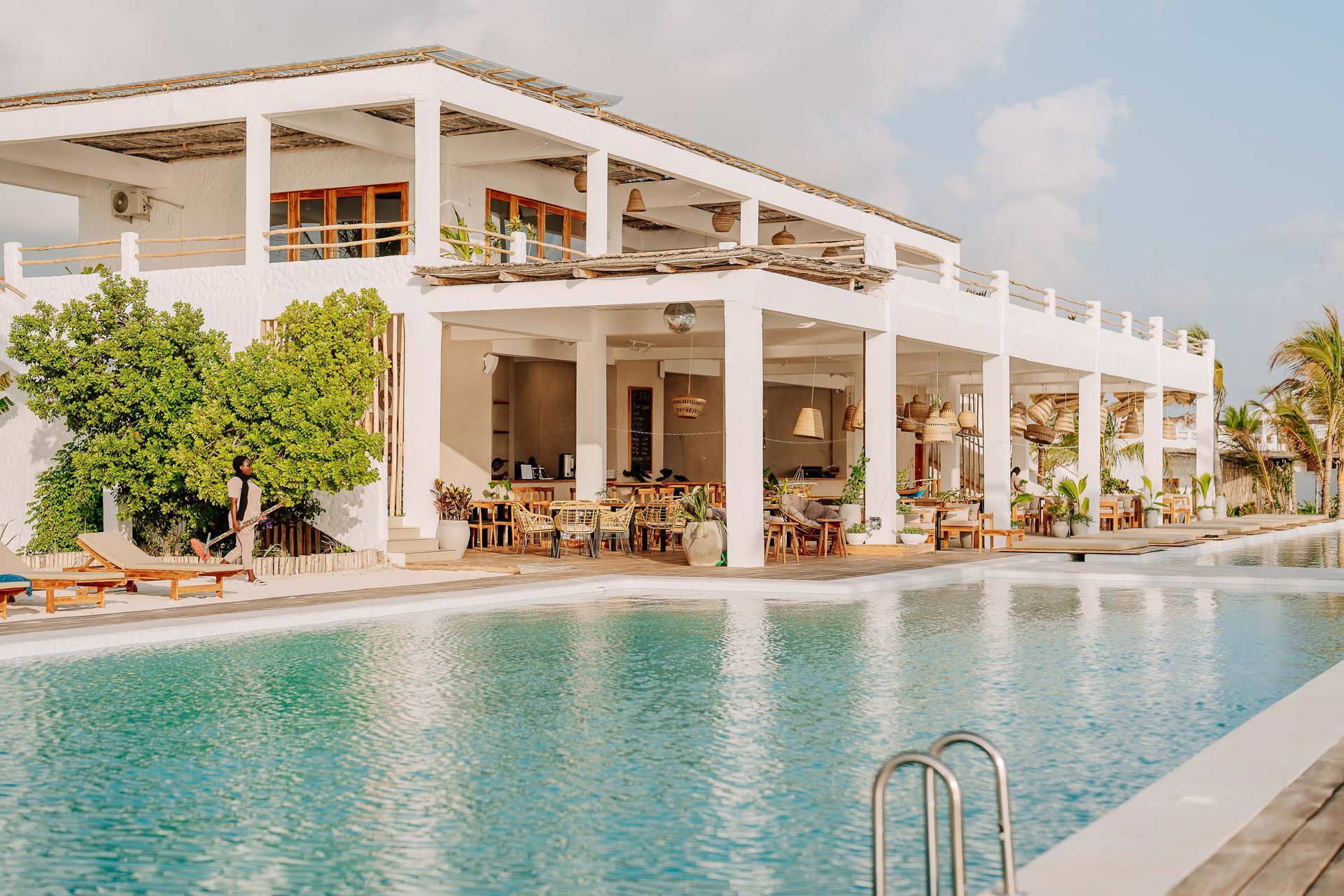 Luxury white villa with a turquoise pool and outdoor dining terrace by the water