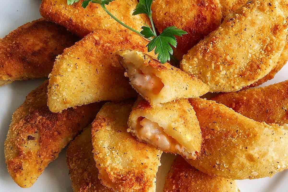 Golden-brown fried pastries arranged on a plate, garnished with a small green herb leaf.