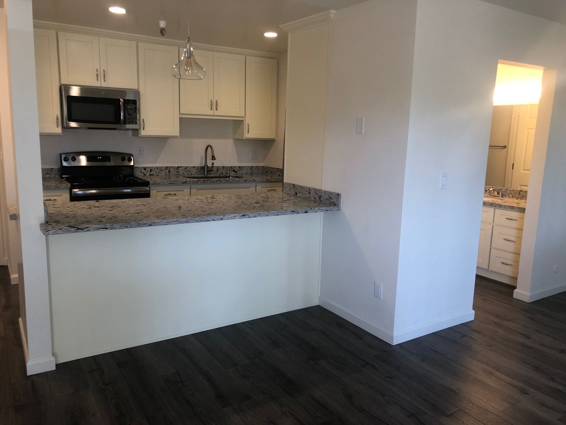 A kitchen with granite counter tops , stainless steel appliances , and white cabinets.