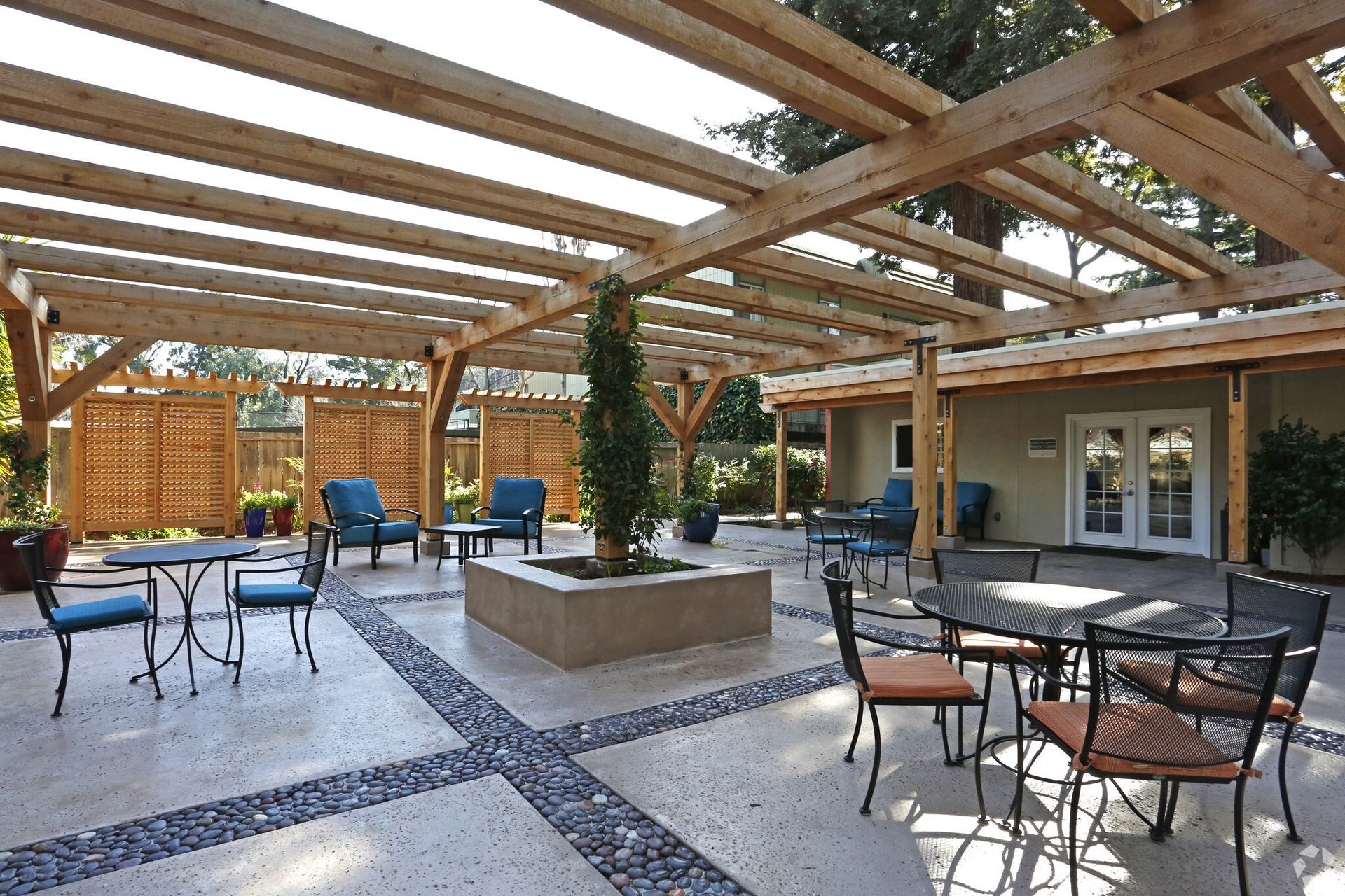 A patio with tables and chairs under a wooden pergola