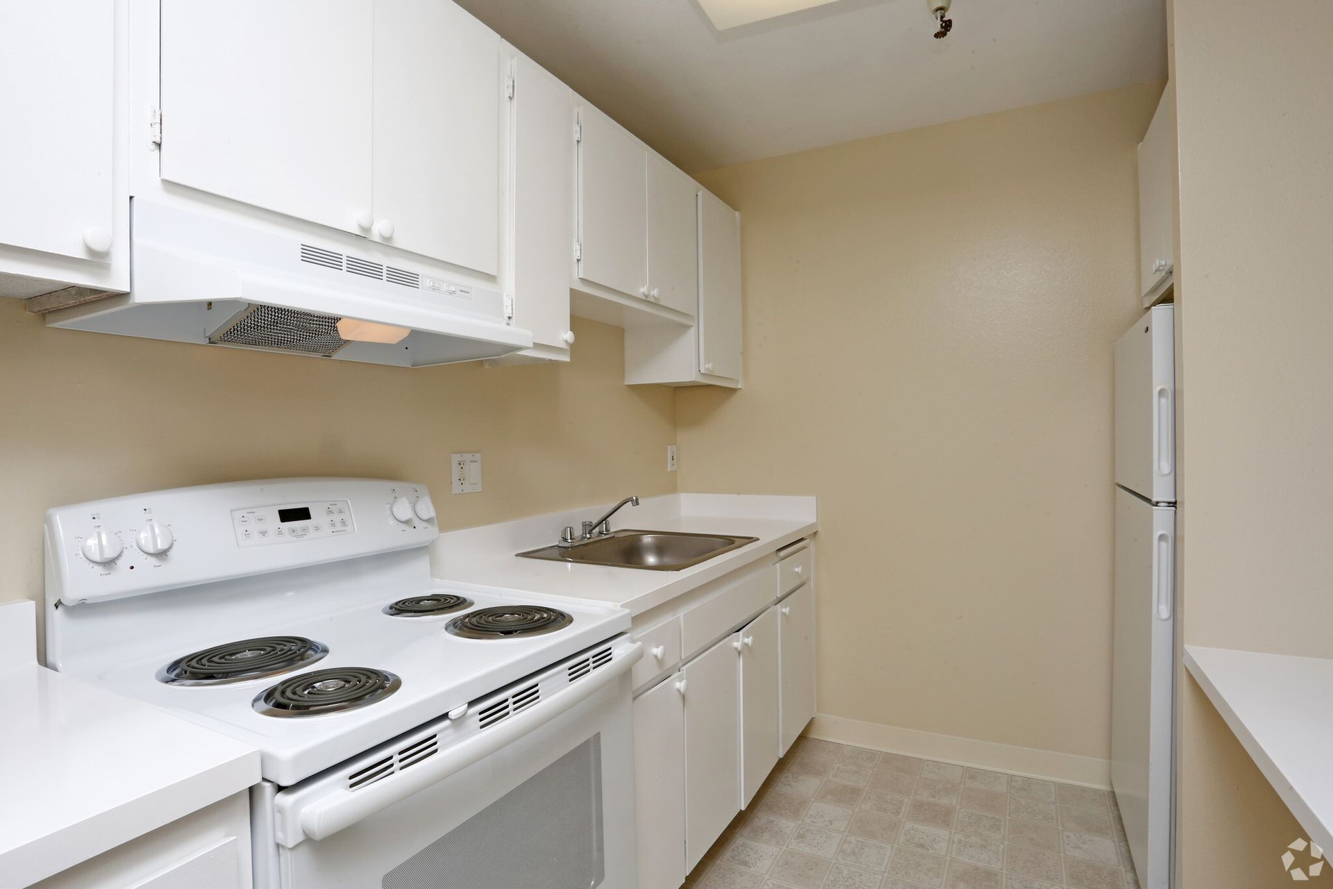 A kitchen with white cabinets and a white stove top oven