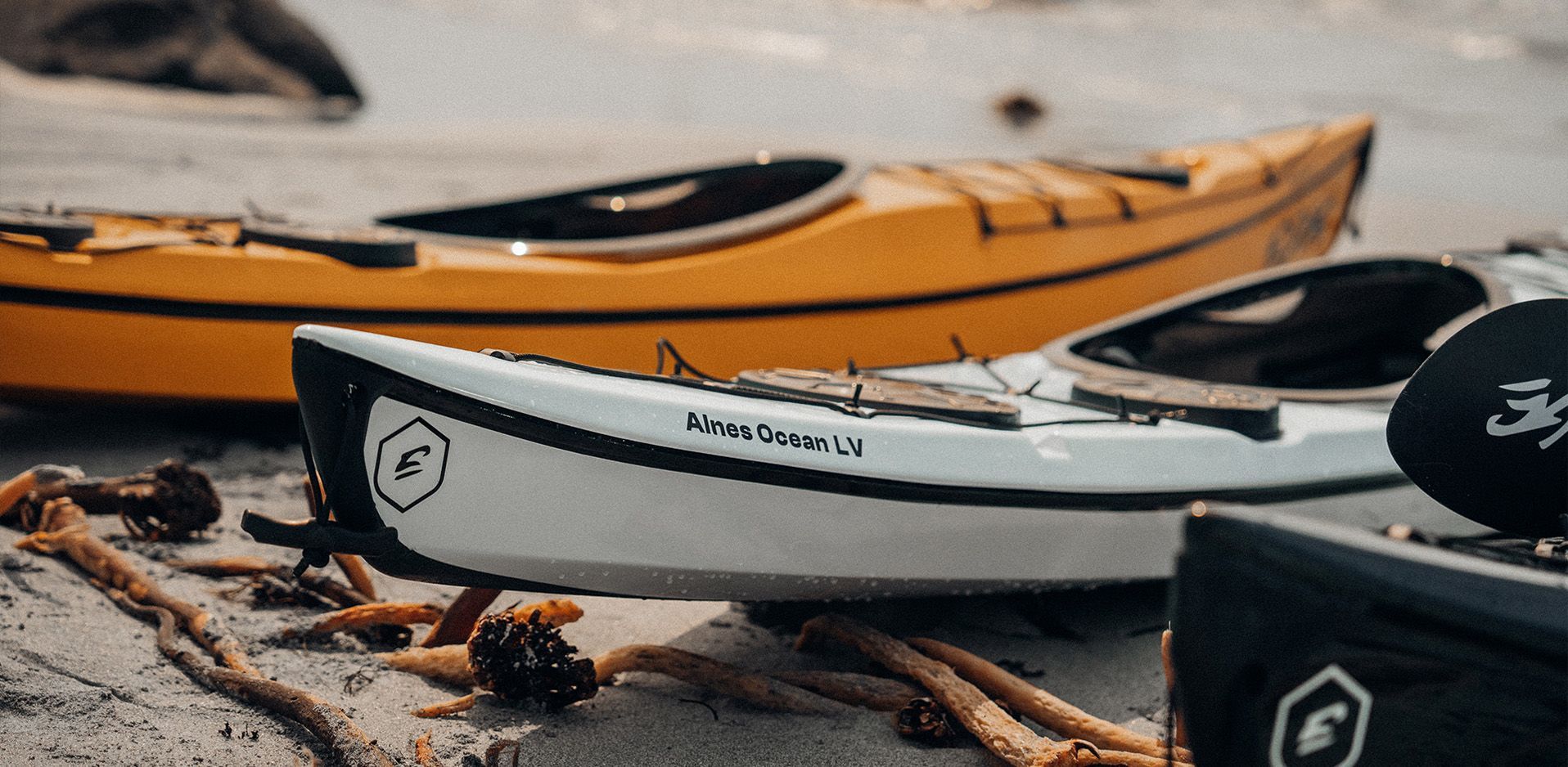 Nærbilde av tre kajakker på en strand.