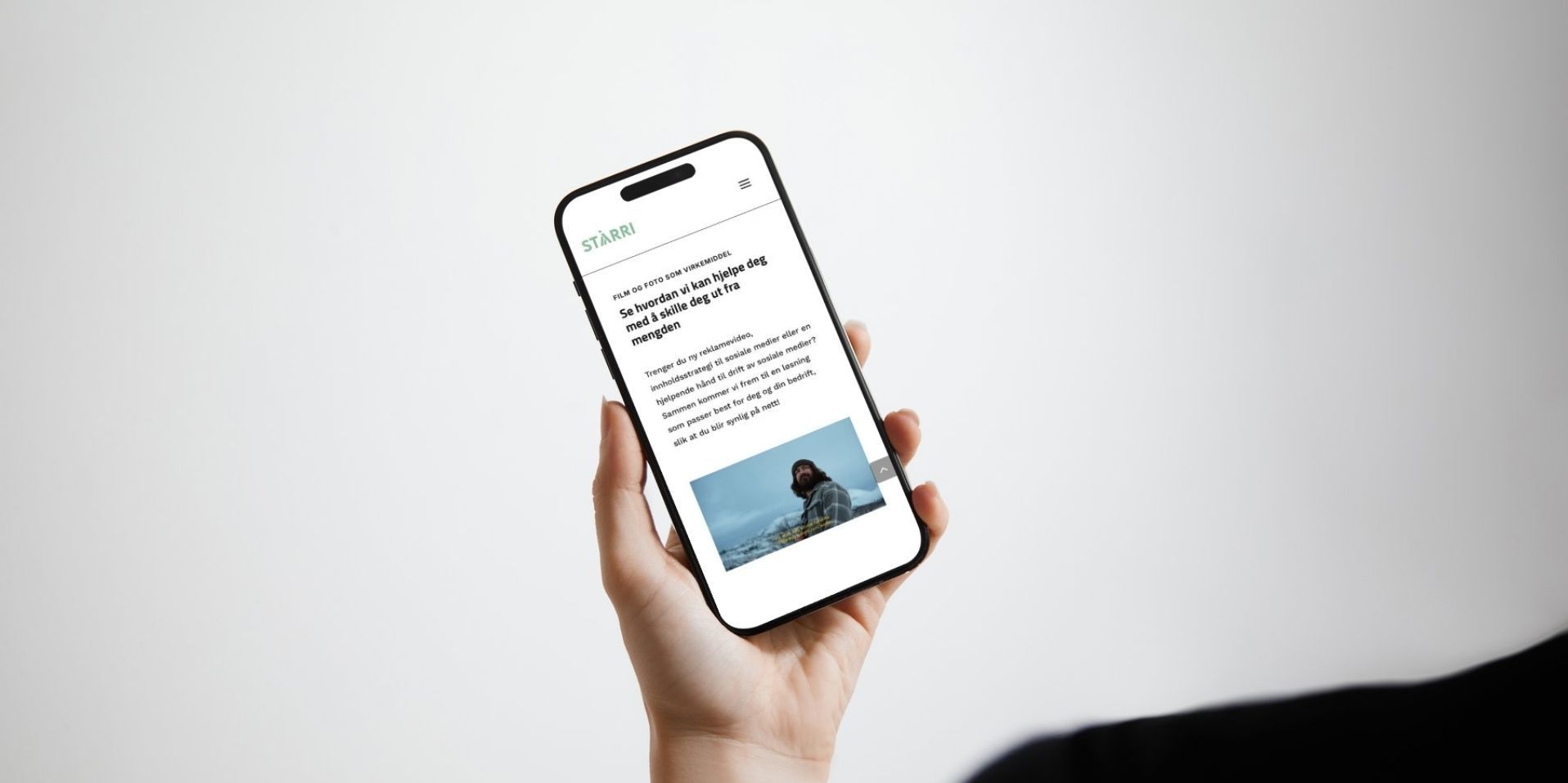 Hånd som holder en Iphone for å vise frem en nettside