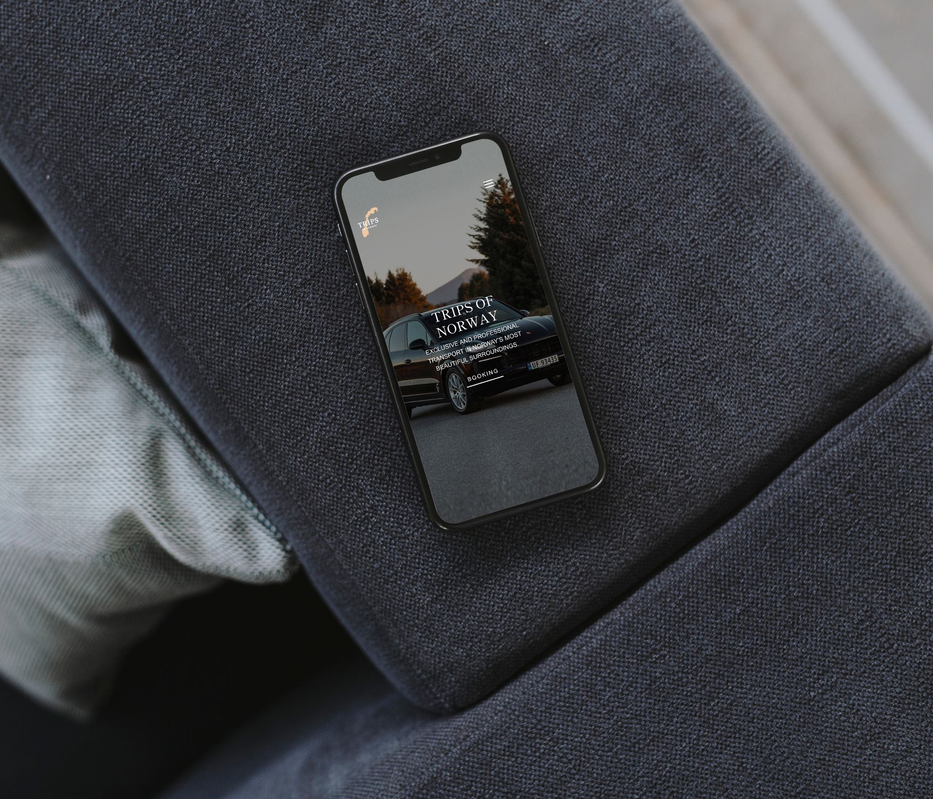 Nærbilde av Iphone som ligger på kanten av en sofa med nettsiden til Trips og Norway åpen.