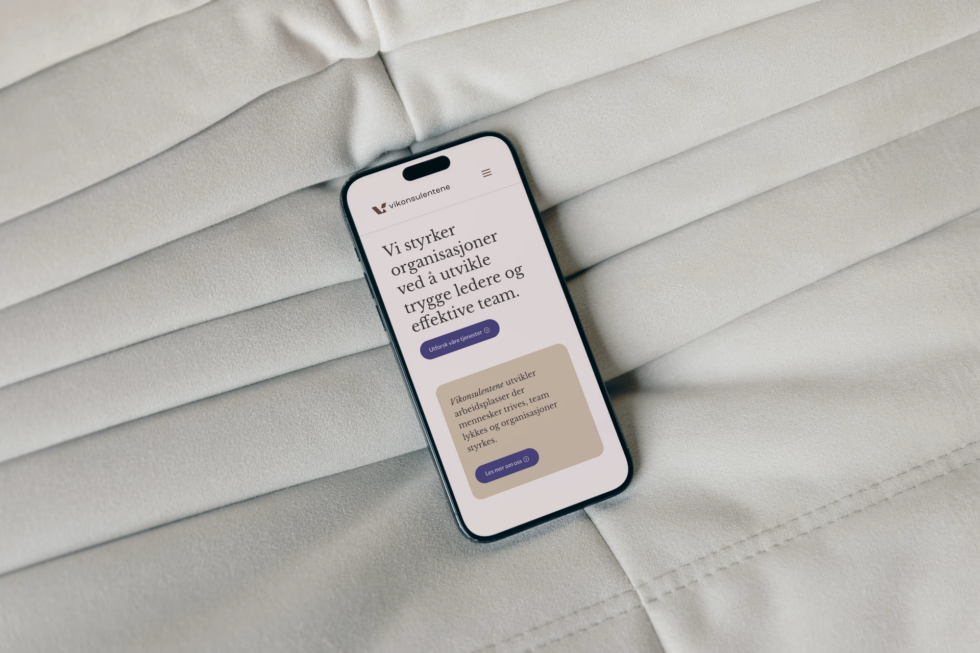 Nærbilde av Iphone  som ligger på en pute med nettside for Vikonsulentene.