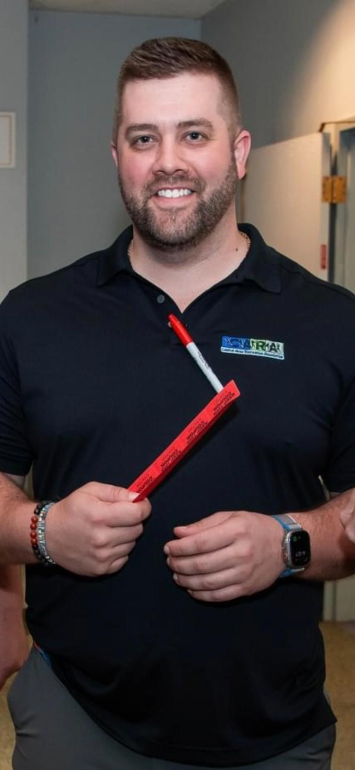 A man wearing glasses and a red tie is smiling for the camera.
