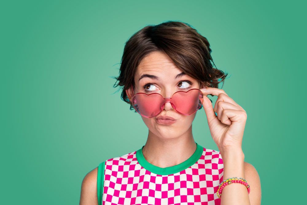 A woman wearing sunglasses and a checkered shirt is making a funny face.