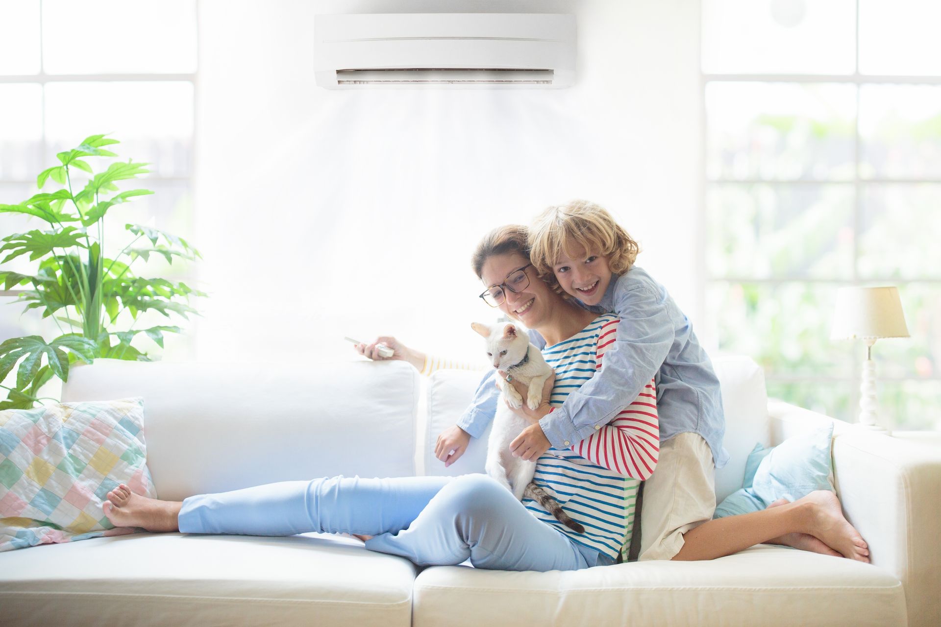 A woman and a child are sitting on a couch with a dog.