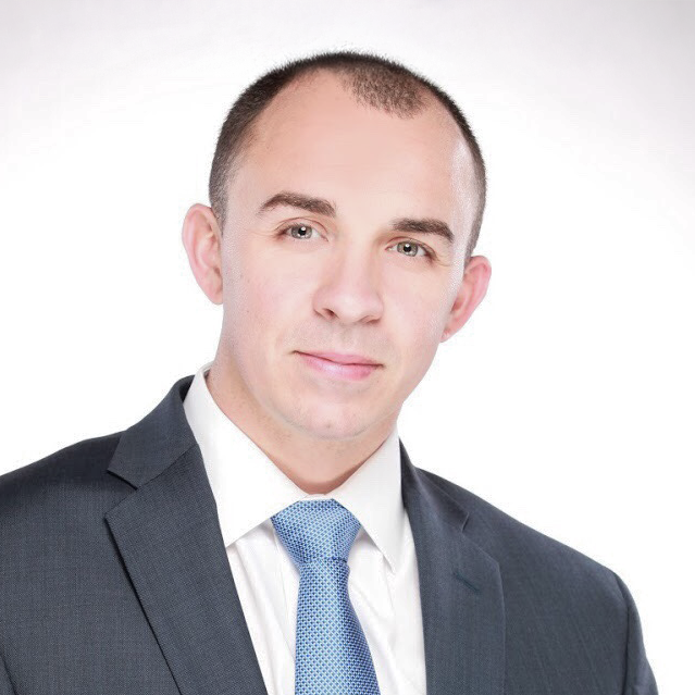 A man in a suit and tie looks at the camera