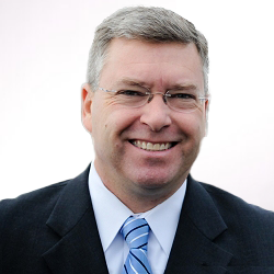 A man in a suit and tie smiles for the camera