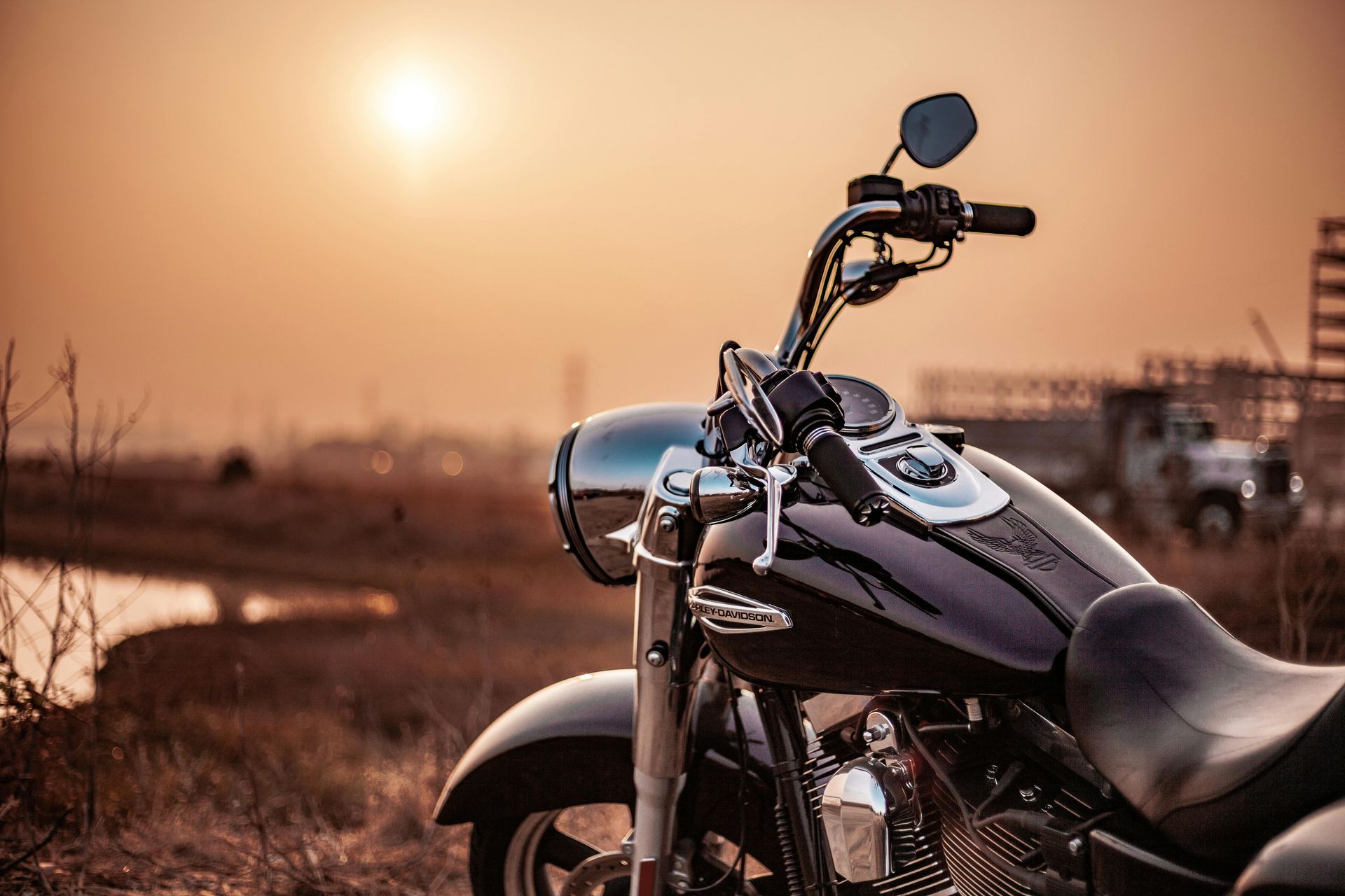 A motorcycle is parked in a field at sunset.