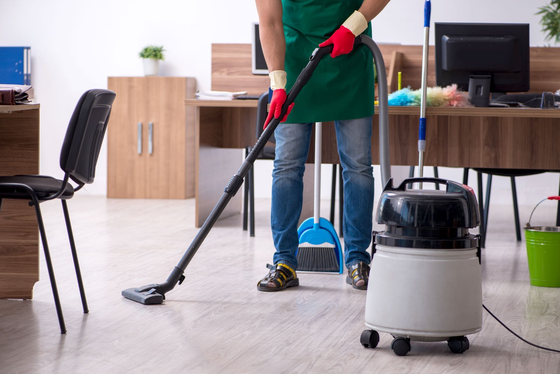 A man is cleaning the floor of an office with a vacuum cleaner.