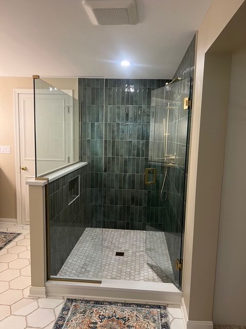 A modern walk-in shower with dark vertical tiles, a white stone floor, and glass panels, located in a neutral bathroom.