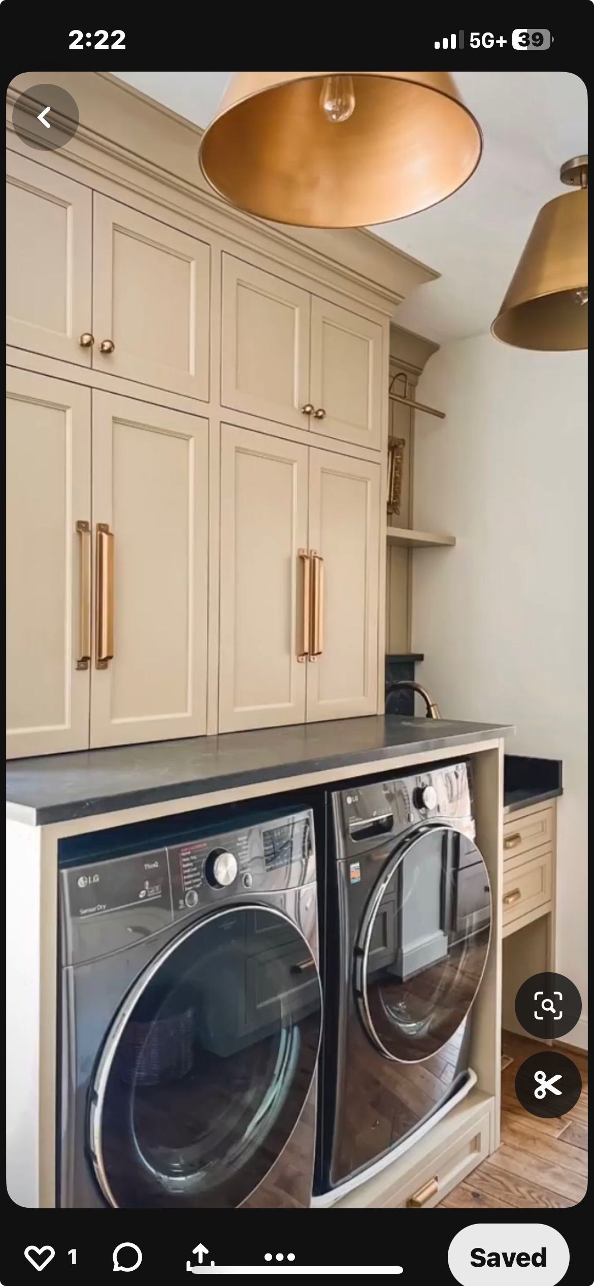 Laundry room with beige cabinetry, gold hardware, hanging pendant lights, and side-by-side stainless steel washers.