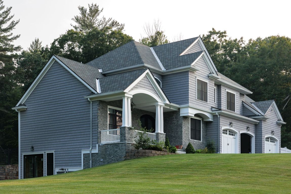 A large gray house with a porch and two garages