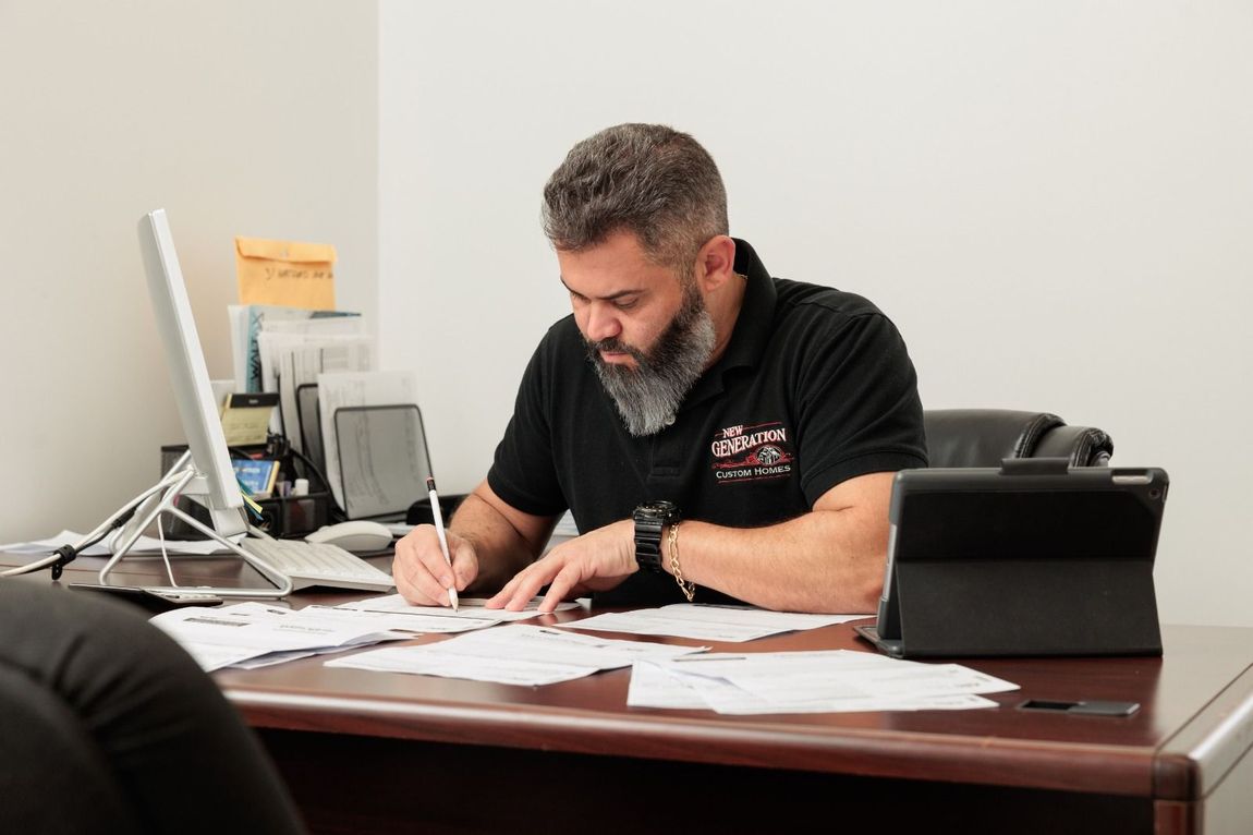 A man with a beard is sitting at a desk in front of a computer.