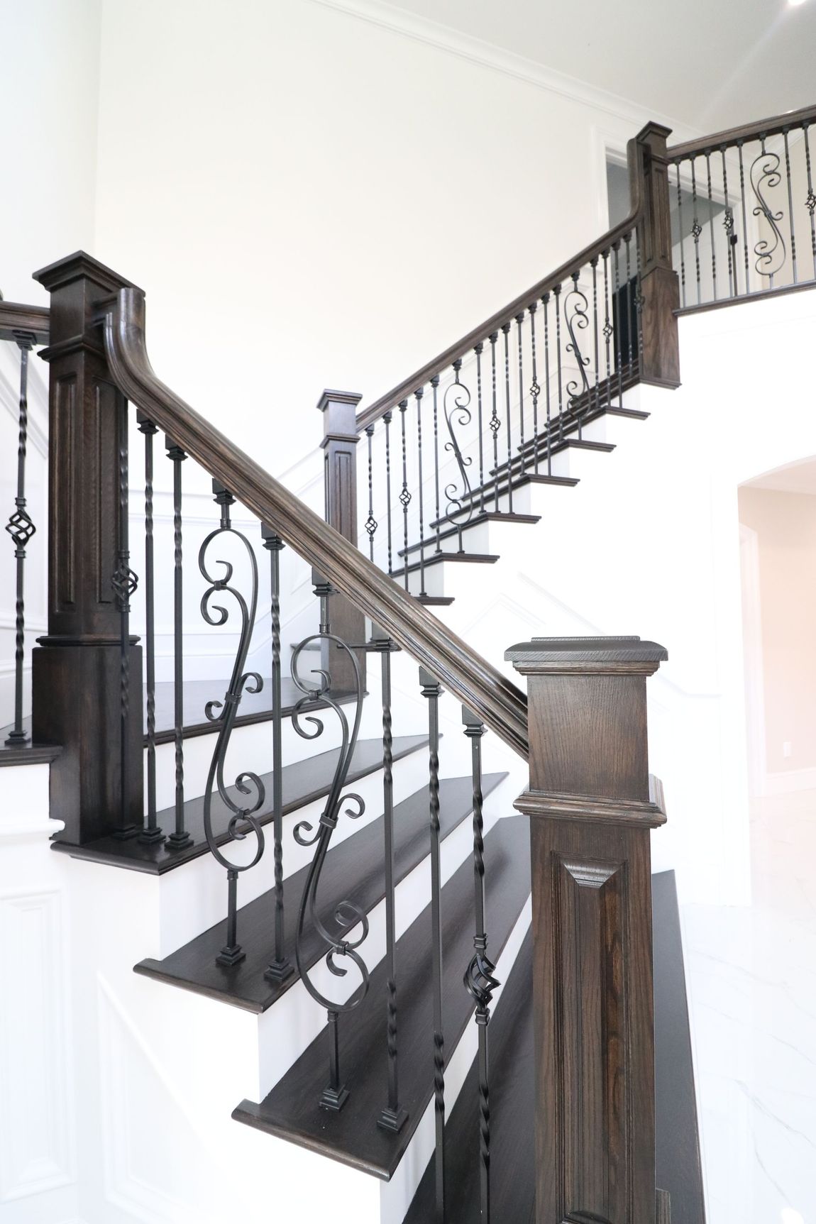 A staircase with a wrought iron railing and wooden steps