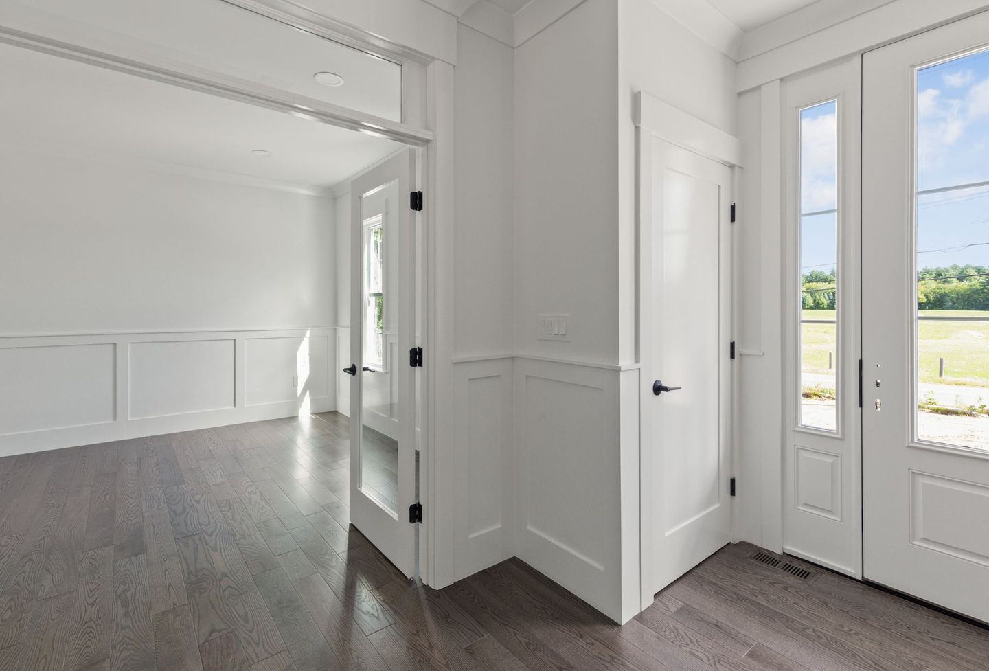 An empty room with hardwood floors and white walls in a house.