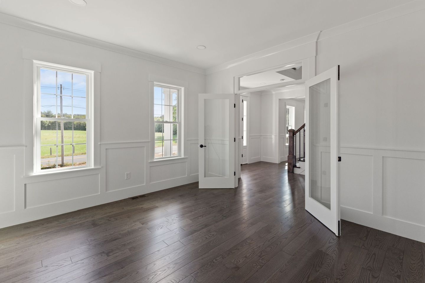 An empty living room with hardwood floors and white walls.