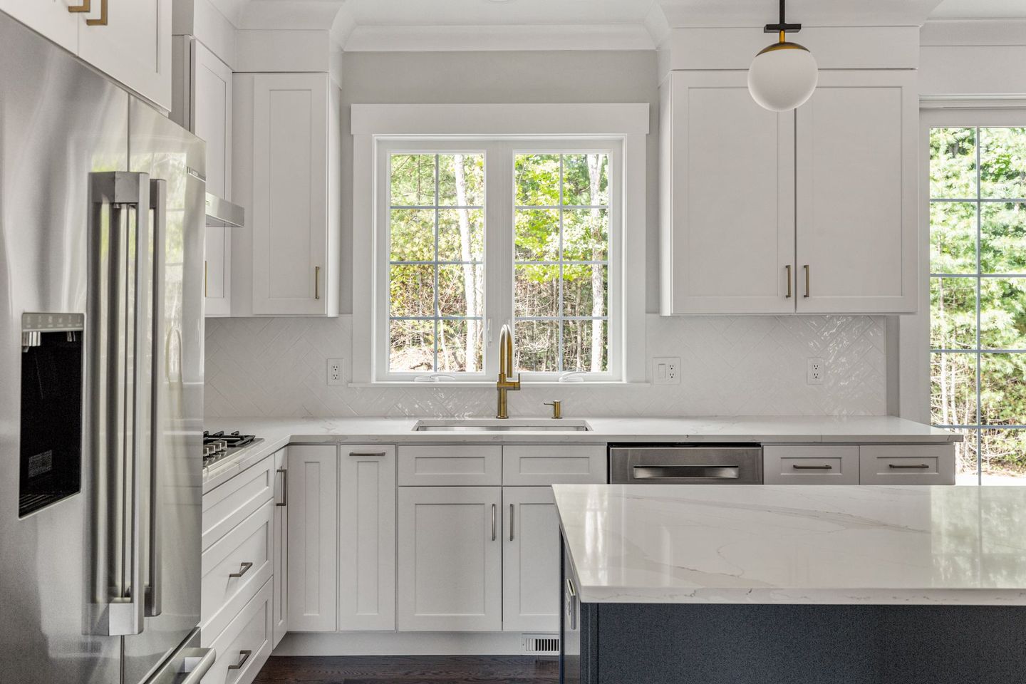 A kitchen with white cabinets , stainless steel appliances , a sink , and a window.