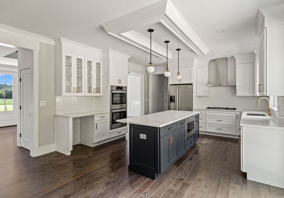 A kitchen with white cabinets and a large island in the middle.