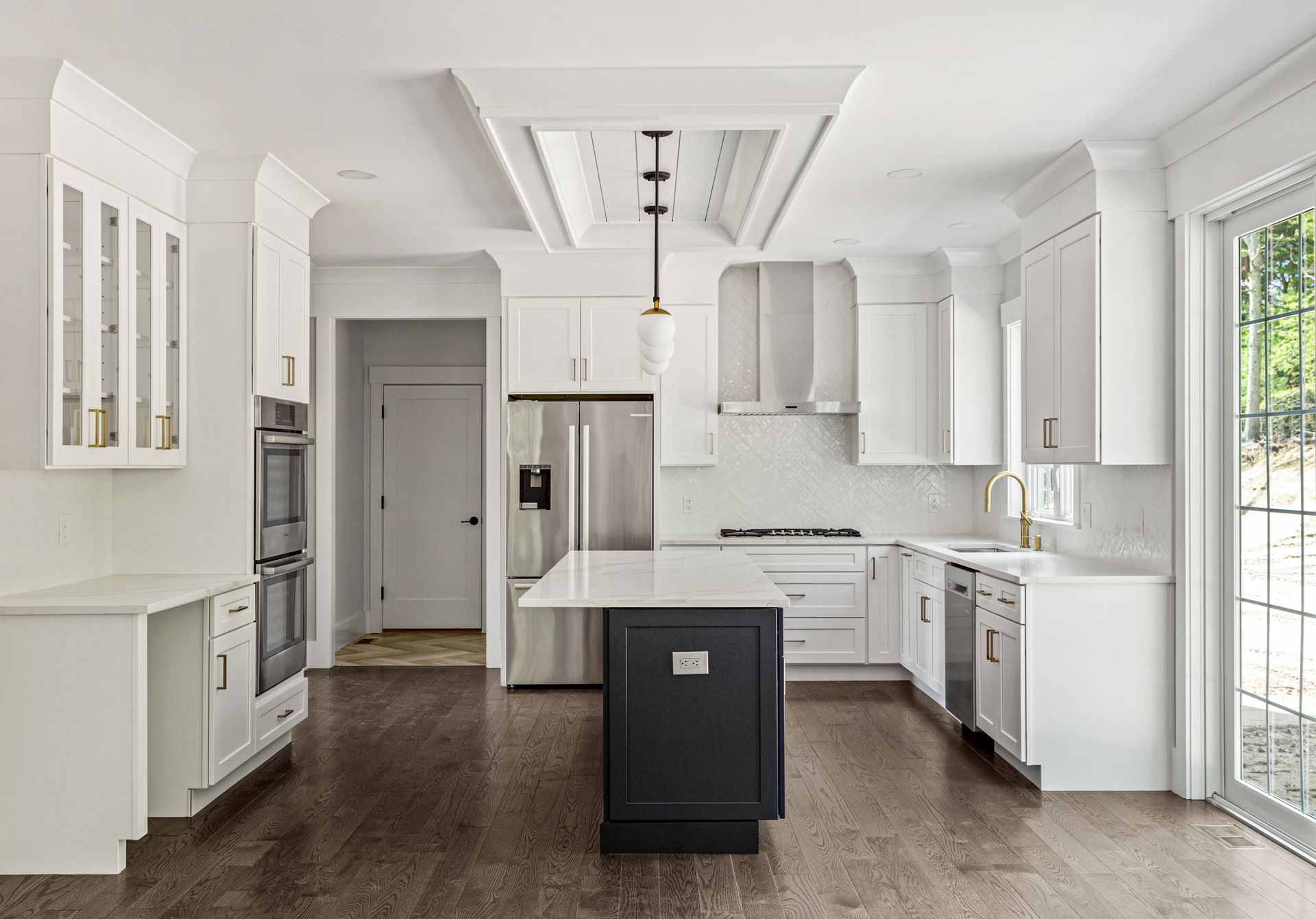 A kitchen with white cabinets , stainless steel appliances , and a large island.