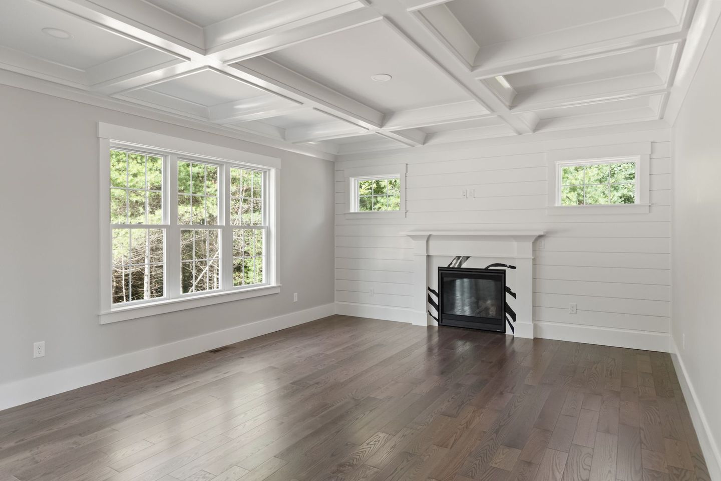 An empty living room with hardwood floors and a fireplace.