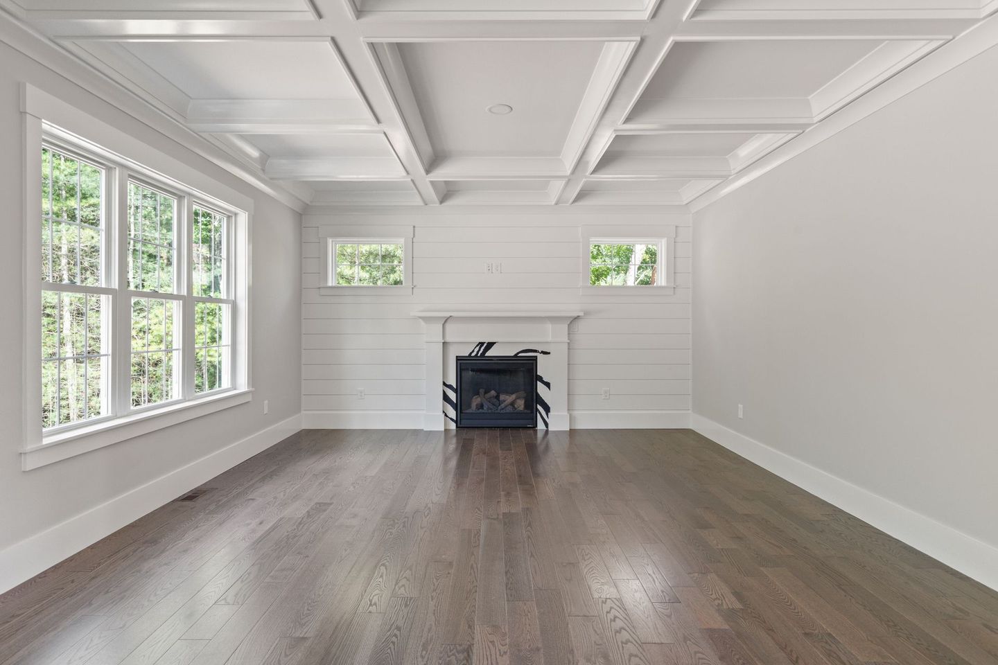 An empty living room with hardwood floors and a fireplace.