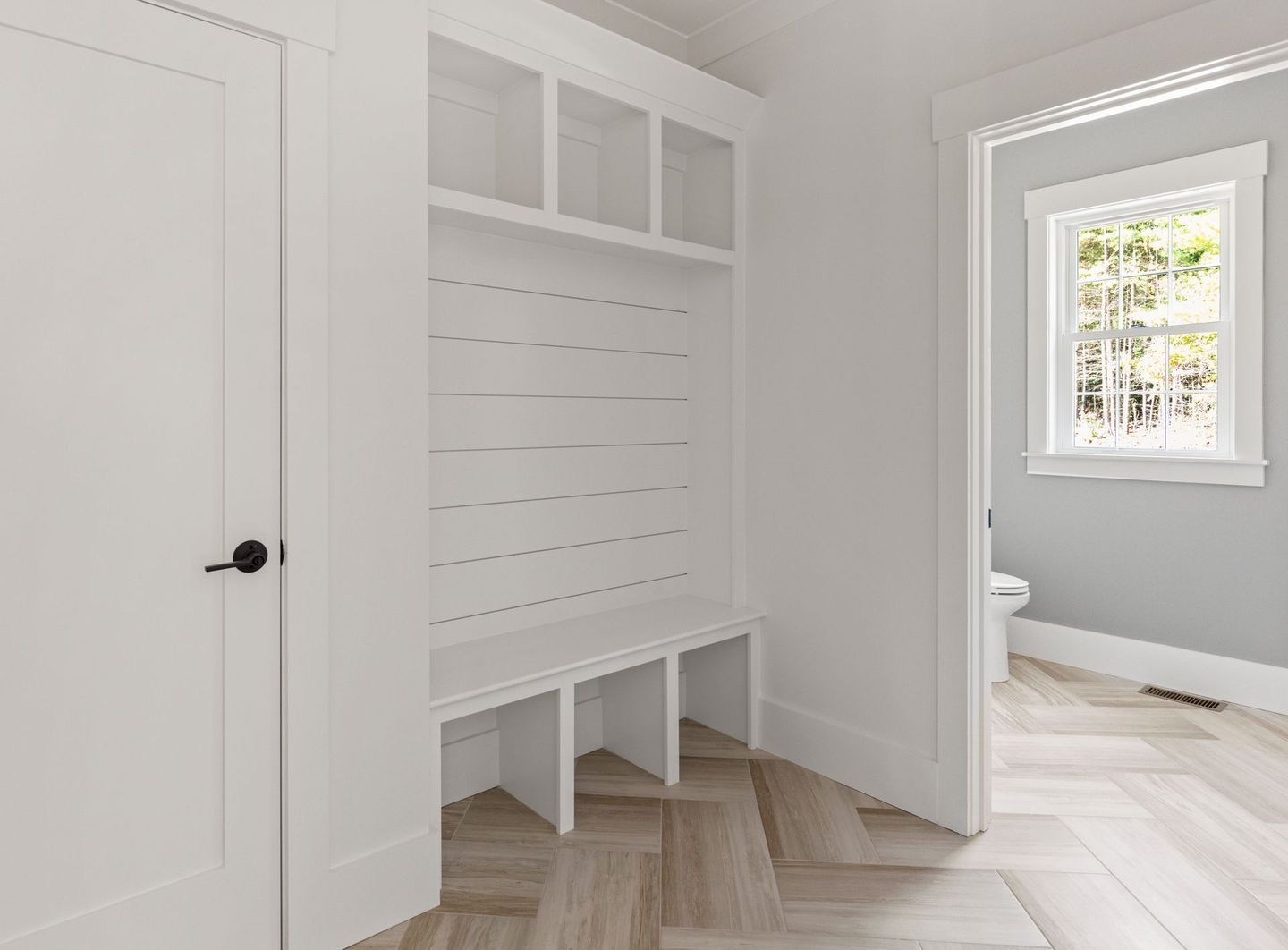 A hallway with a bench and shelves in a house.