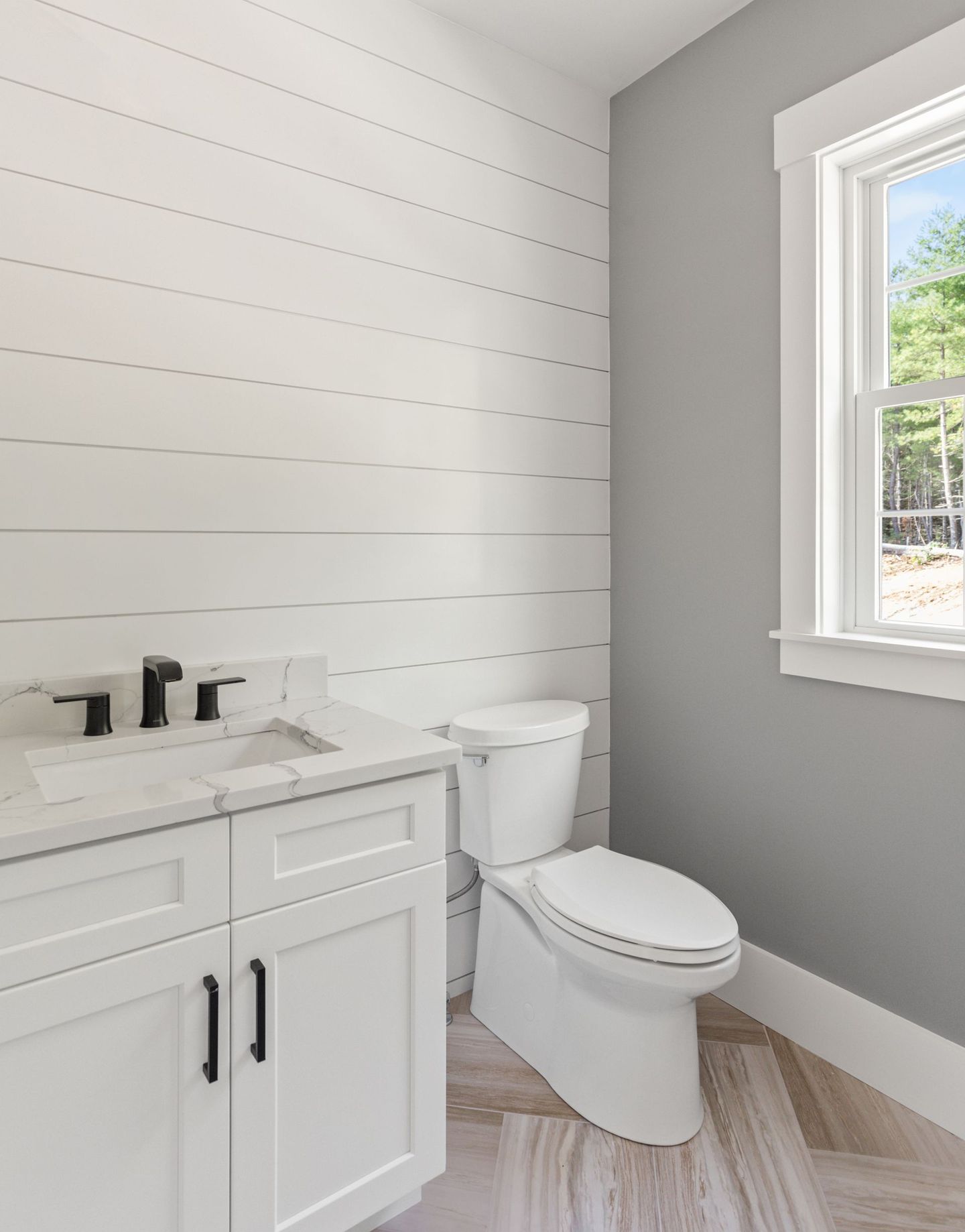 A bathroom with a toilet , sink , and window.