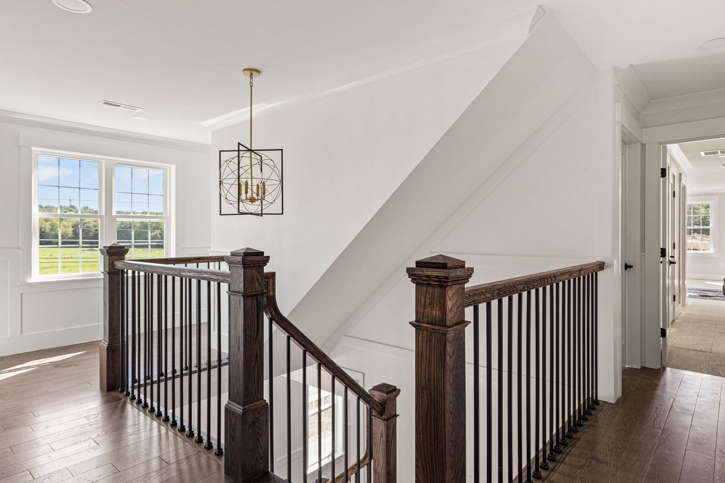 A staircase in a house with a wooden railing and a chandelier hanging from the ceiling.