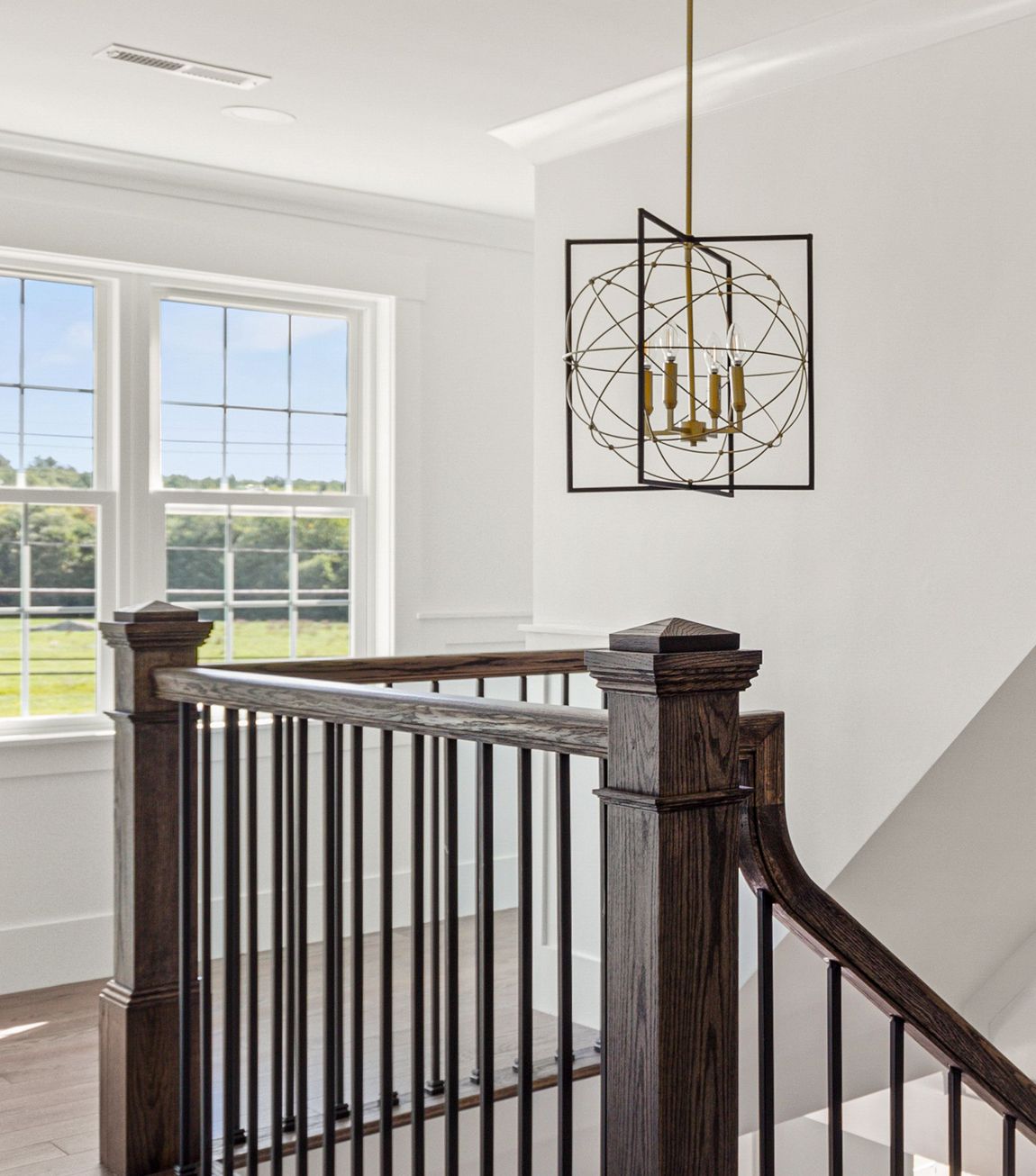 A staircase with a wooden railing and a chandelier hanging from the ceiling.