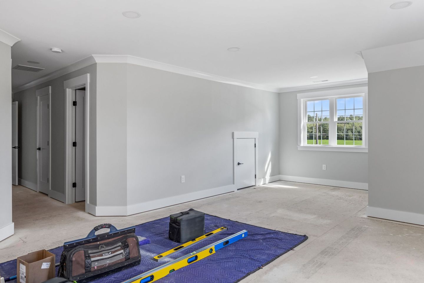 An empty room with a blue rug and tools on the floor.