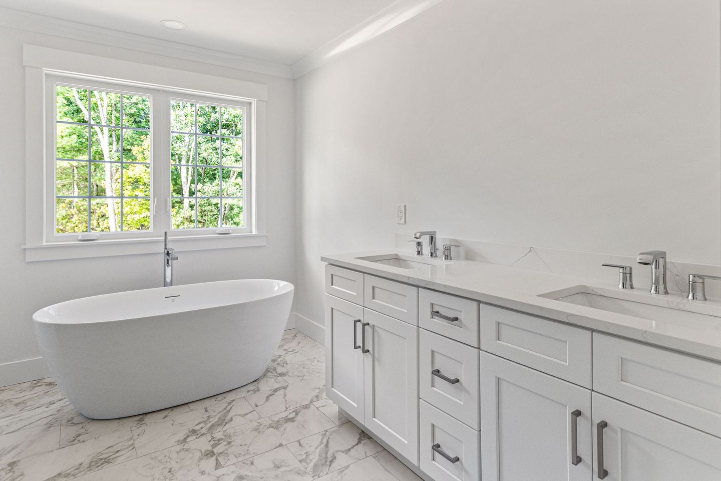 A bathroom with a tub , sinks , cabinets and a window.