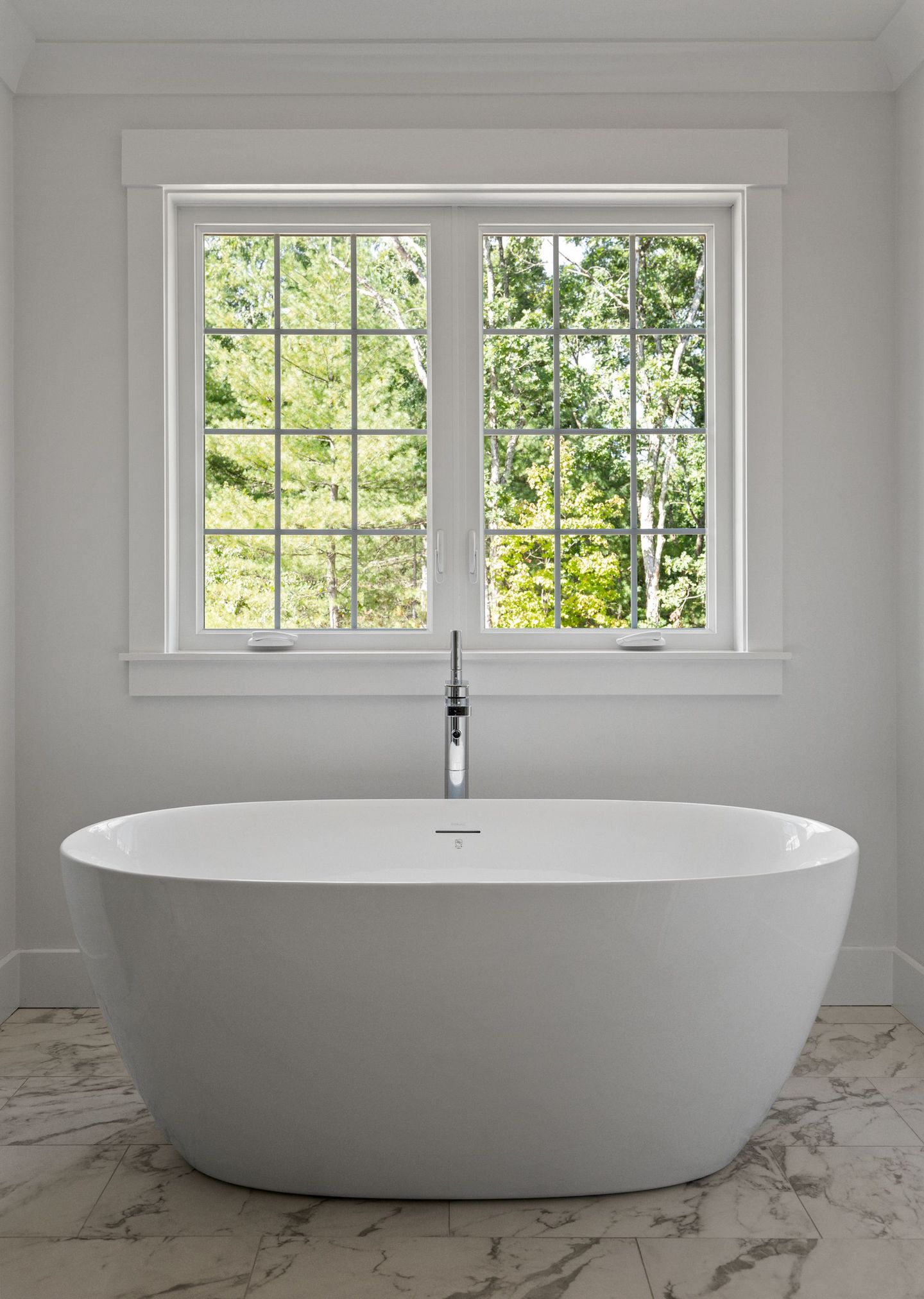 A white bathtub in a bathroom next to a window.