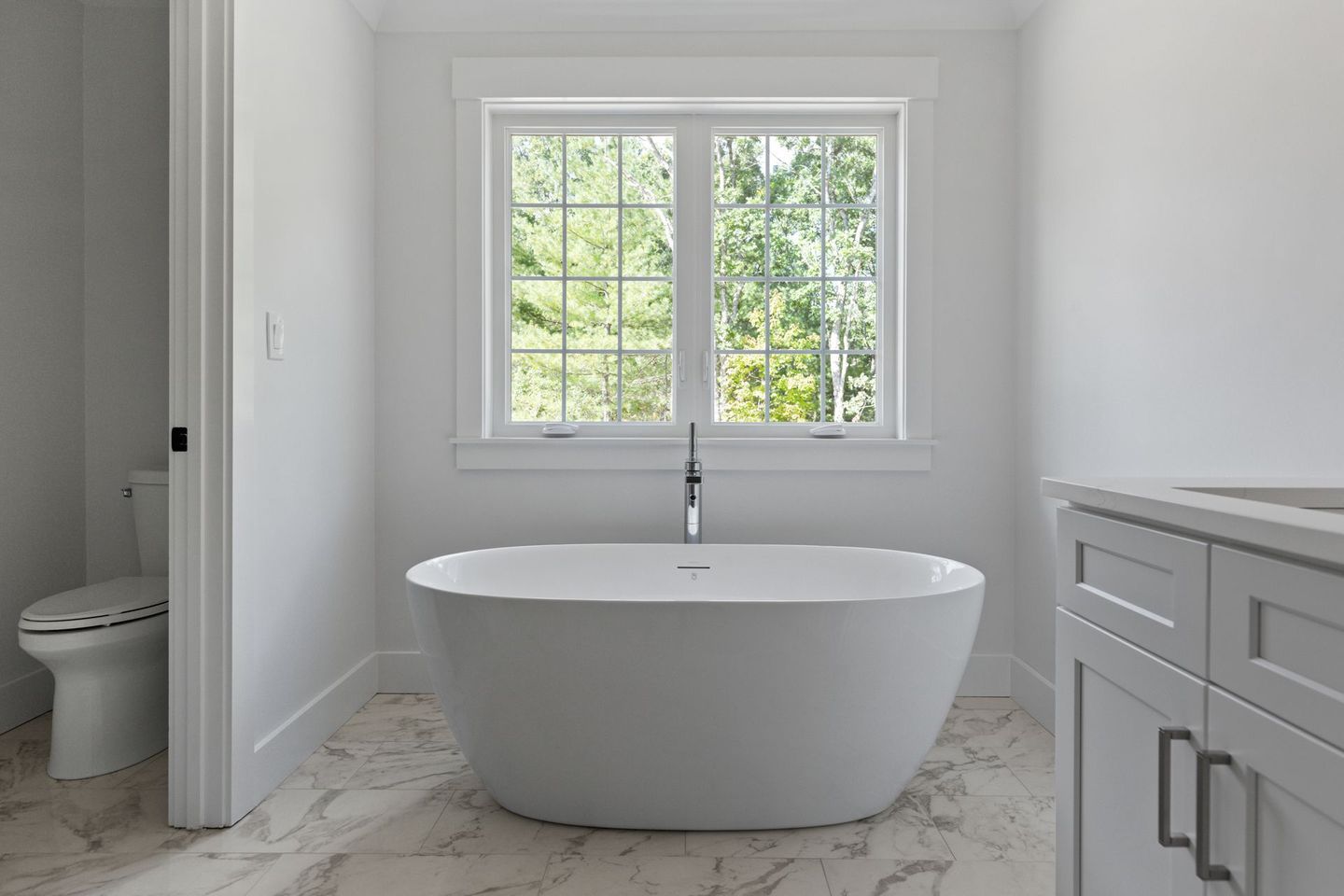 A bathroom with a bathtub , toilet and window.