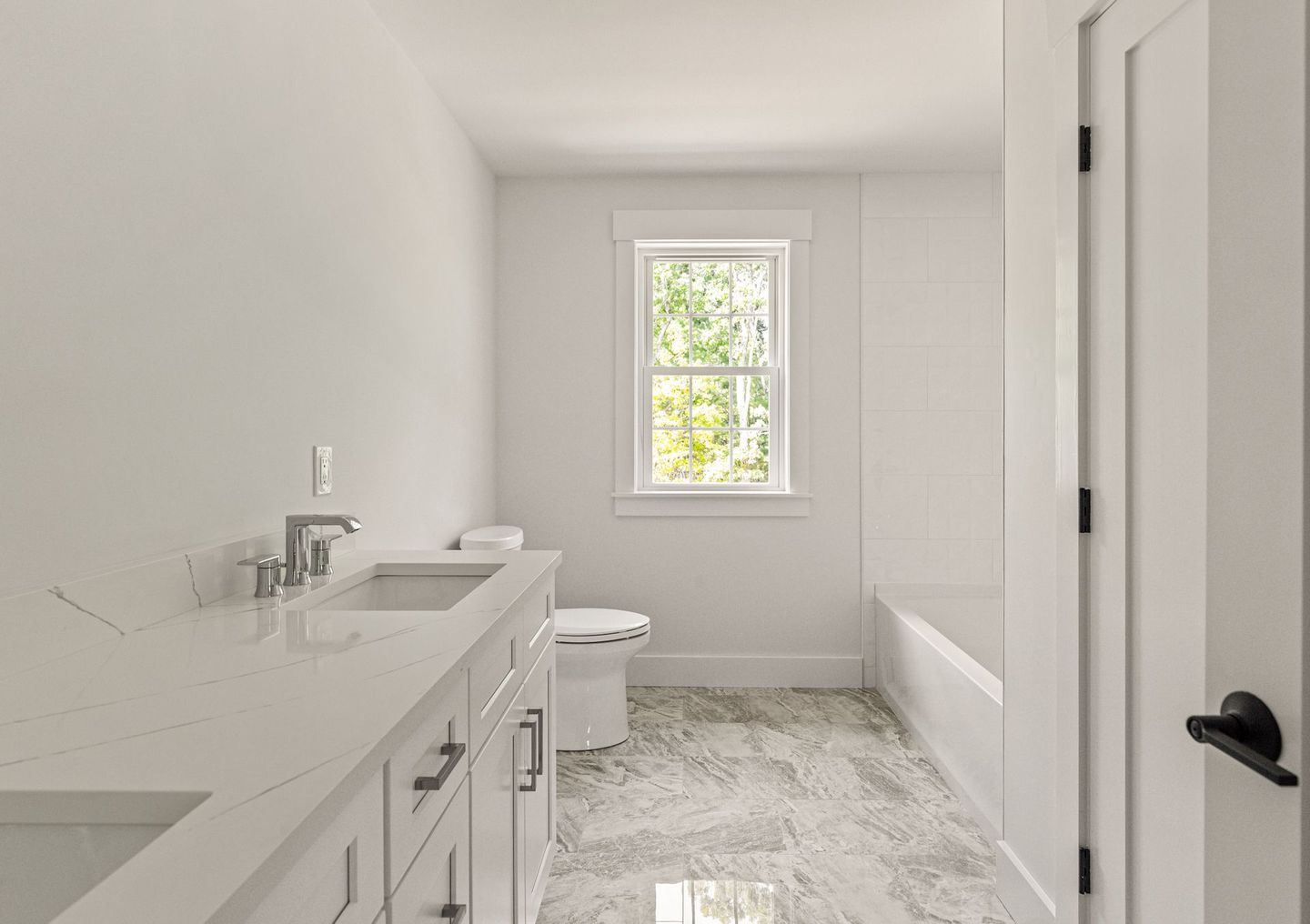 A bathroom with a sink , toilet , bathtub and window.