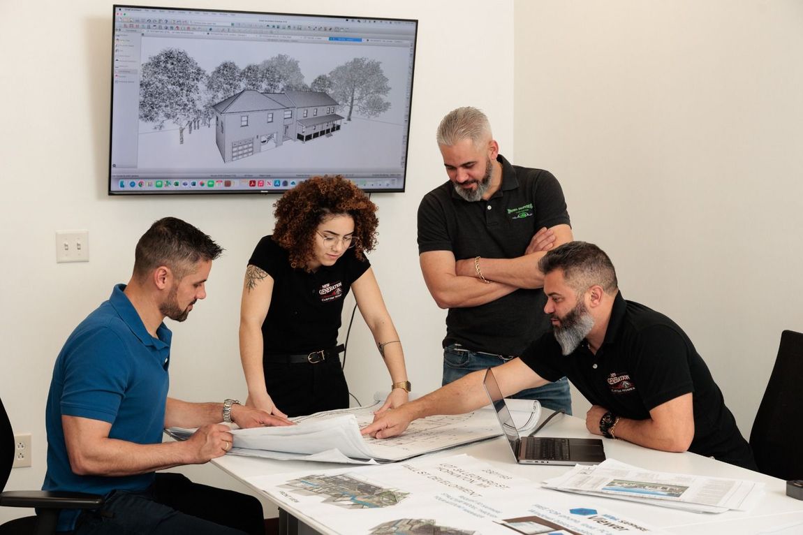 A group of people are sitting around a table looking at a blueprint.