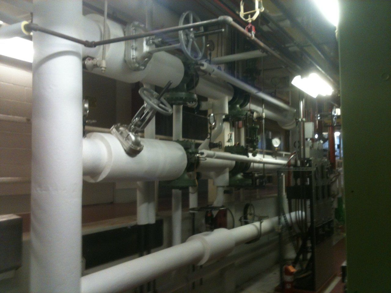 White-insulated pipes with valves and a control system in an industrial setting.
