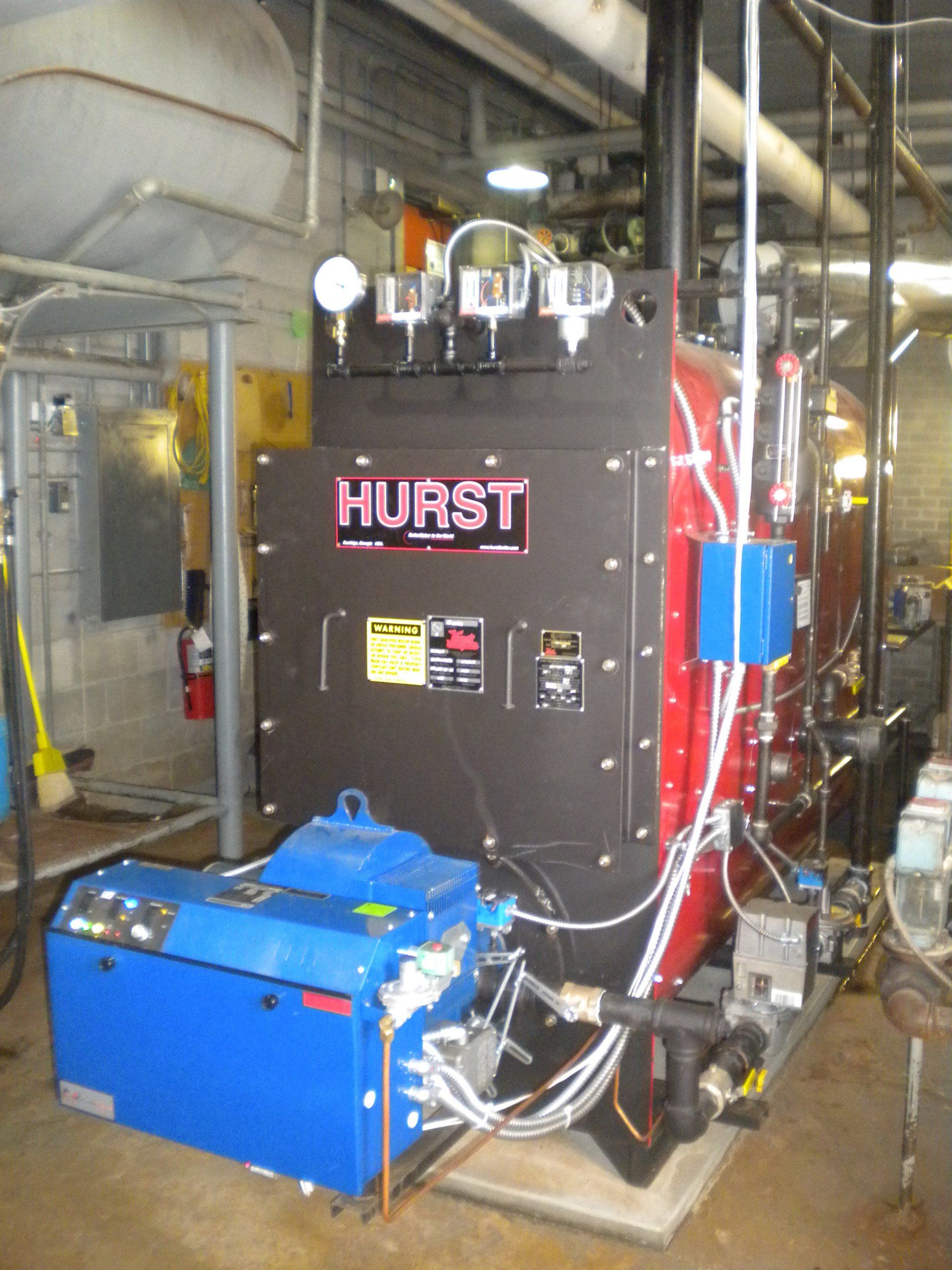A Hurst industrial boiler with a blue burner, gauges, and controls in a mechanical room.