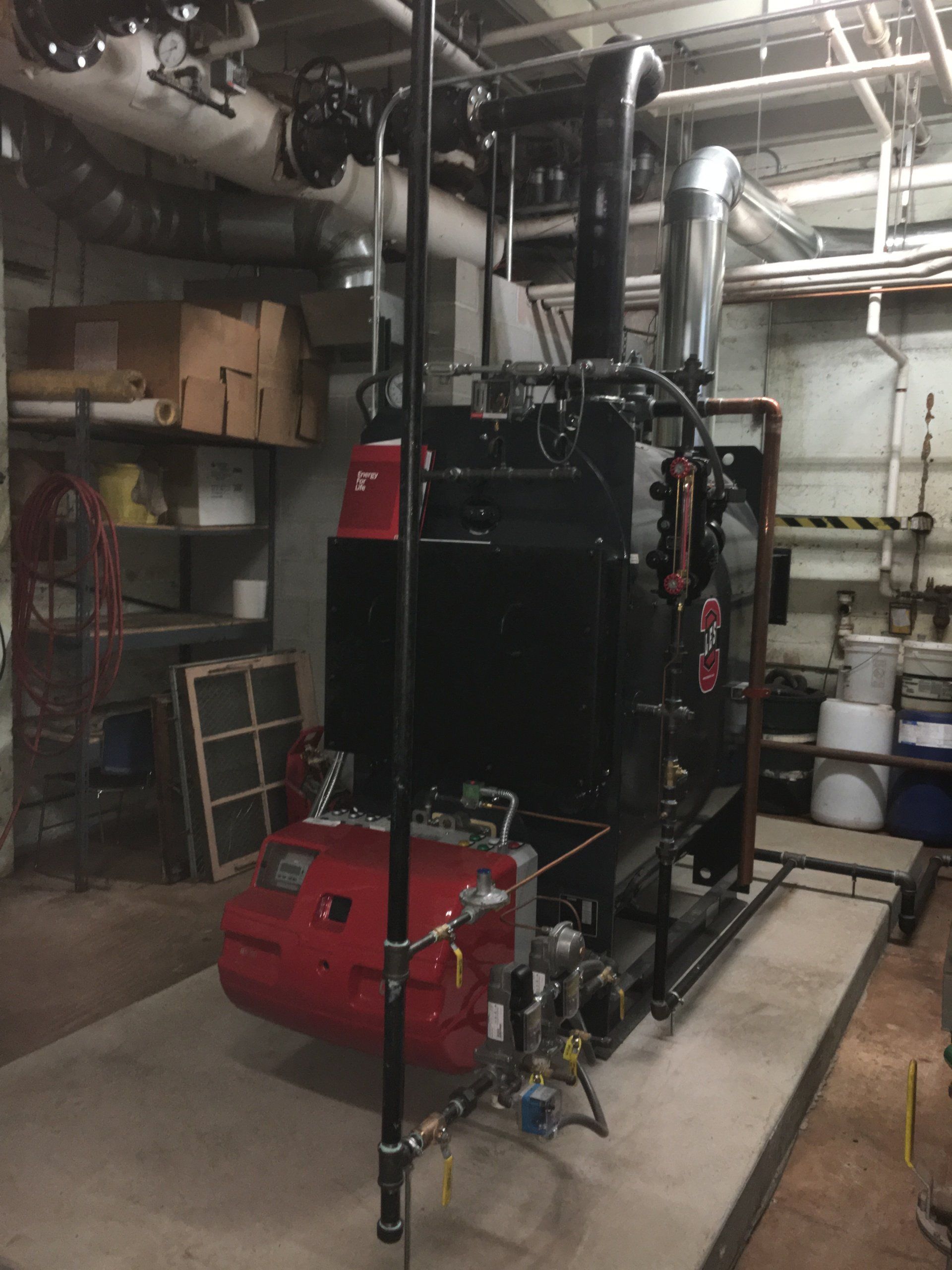 Black and red industrial boiler in a utility room.