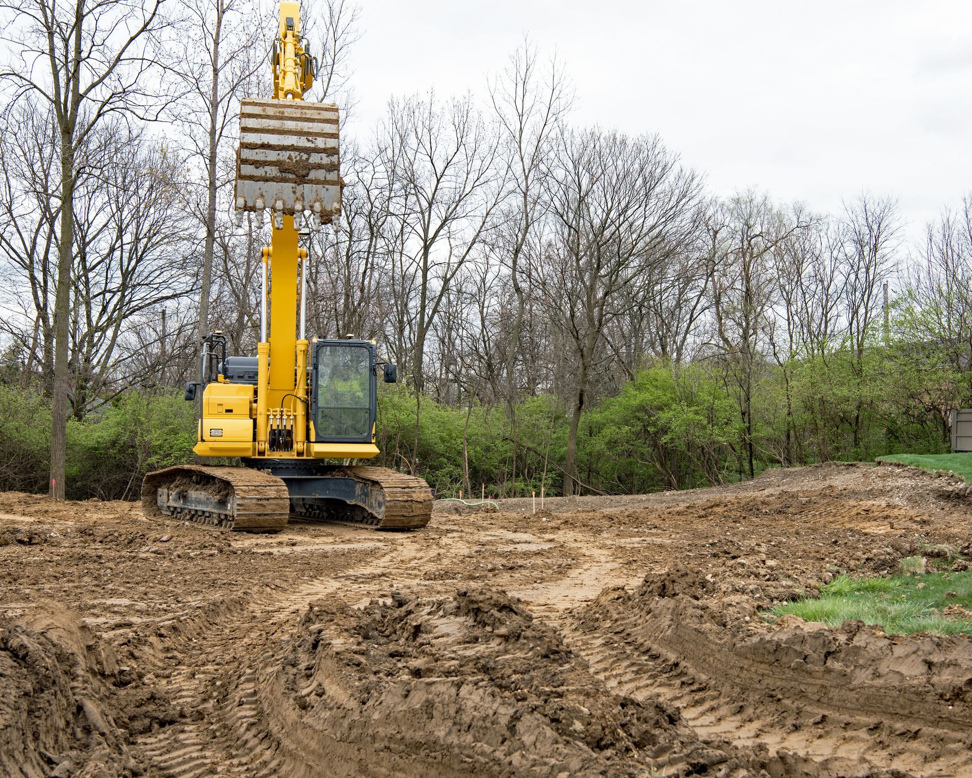 A yellow excavator is moving dirt in a muddy field.