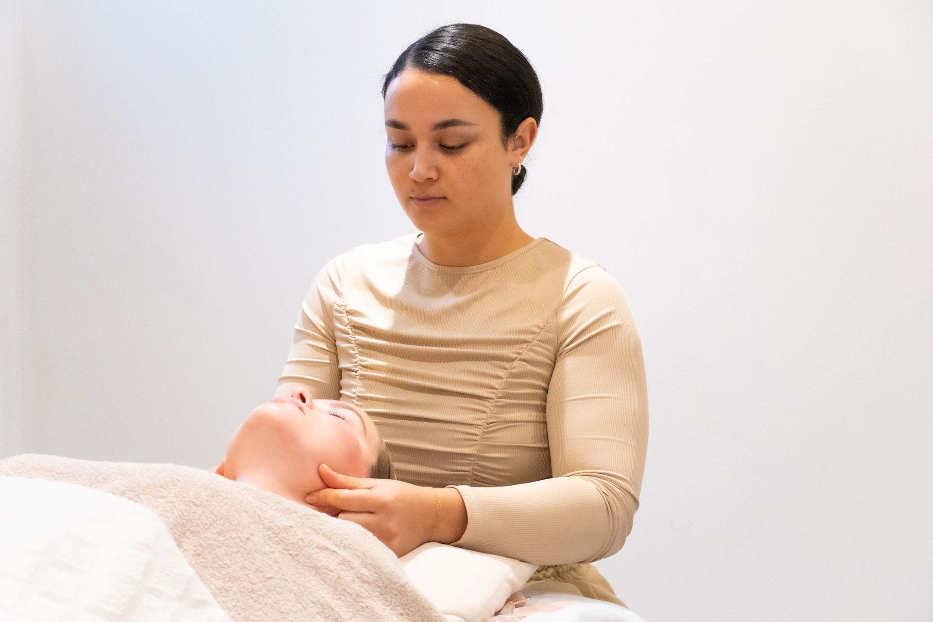 Een vrouw geeft een bindweefselmassage aan het gezicht van een andere vrouw.