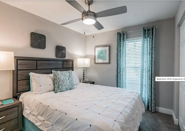 A bedroom with a king size bed and a ceiling fan.