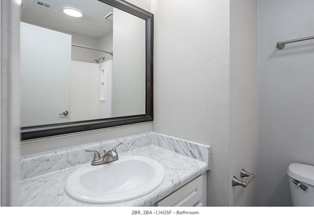 A bathroom with a sink , mirror and toilet.