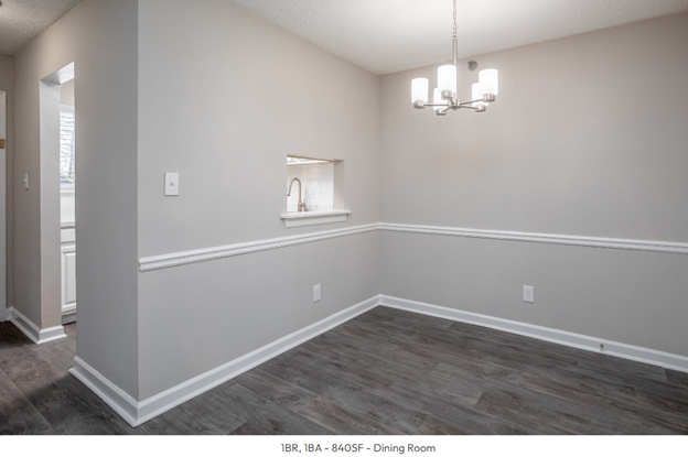 An empty dining room with a chandelier hanging from the ceiling