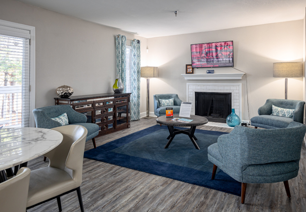 A living room with a fireplace , chairs , a table and a television.