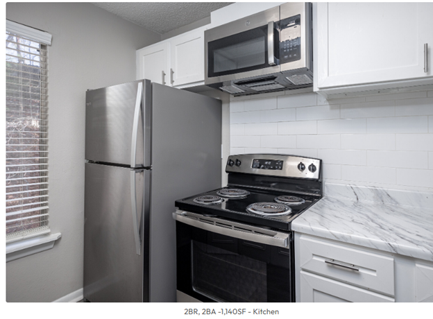 A kitchen with a refrigerator , stove , and microwave.