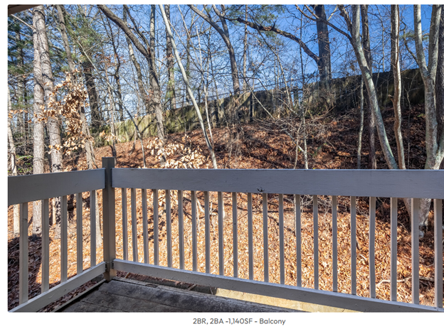 A picture of a balcony with a fence and trees in the background